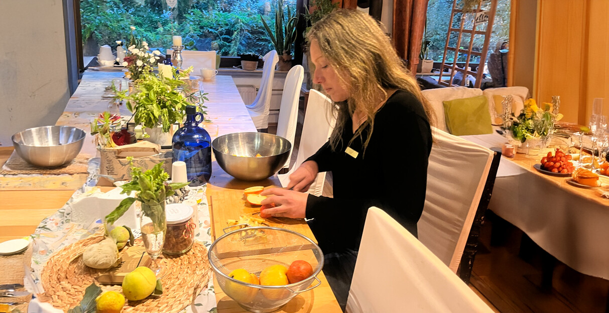 Tine schneidet Zitrusfrüchte an einem Tisch mit frischen Kräutern und Schüsseln.